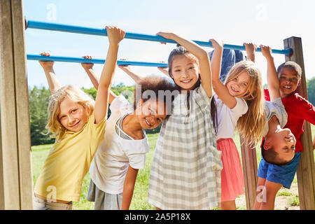 Un gruppo di ragazzi multiculturale su un equipaggiamento sportivo o parco giochi Foto Stock