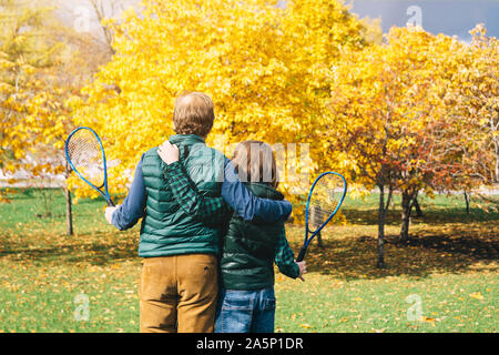 Un padre e figlio di età scolastica con badminton racchetta sta parlando Foto Stock