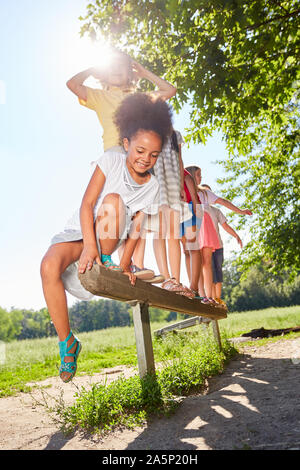 I bambini stanno giocando su un fascio di equilibrio nel parco sul percorso del rivestimento Foto Stock