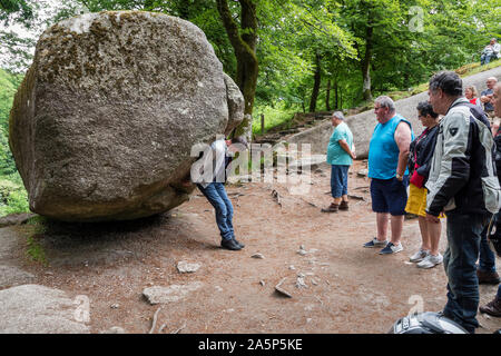 Visitatori cercando di roccia La Roche Tremblante, Huelgoat, Bretagna Francia Foto Stock