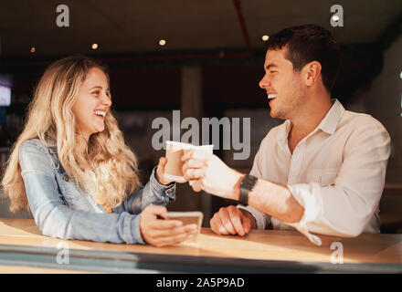 Sorridente giovani amici in una caffetteria di trascorrere del tempo insieme la tostatura con loro monouso Tazze di caffè Foto Stock