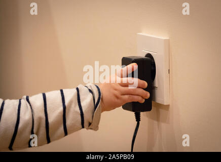 Bambino la mano giocando con presa di alimentazione e il trasformatore elettrico. Primo piano. Foto Stock