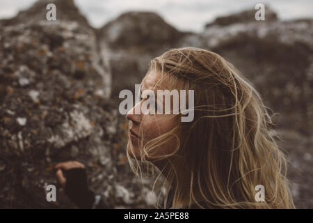 Giovane donna in piedi accanto a rocce Foto Stock