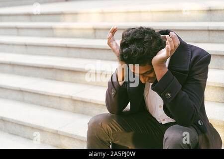 Bel giovane uomo indiano. Udienza triste sui gradini Foto Stock