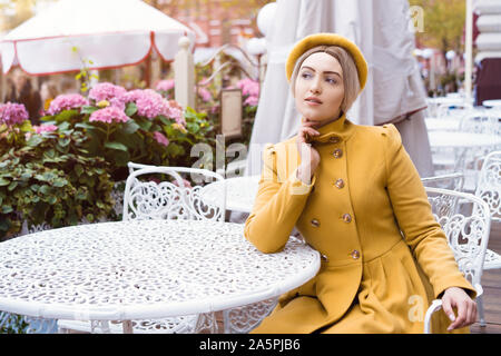 Una bella ragazza bionda è seduta al tavolo in estate caffe Foto Stock