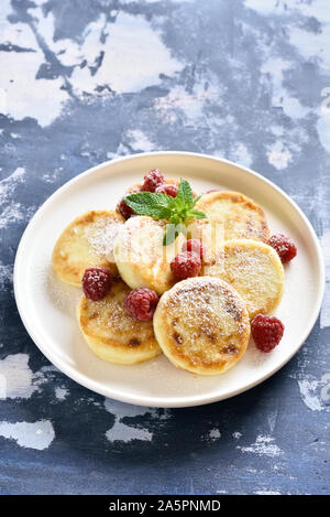 Cottage cheese pancake con lamponi freschi sulla piastra su sfondo di pietra. Foto Stock