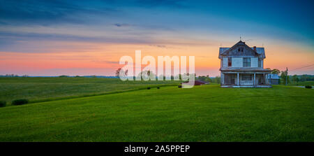 Abbandonata una vecchia fattoria al tramonto. Foto Stock