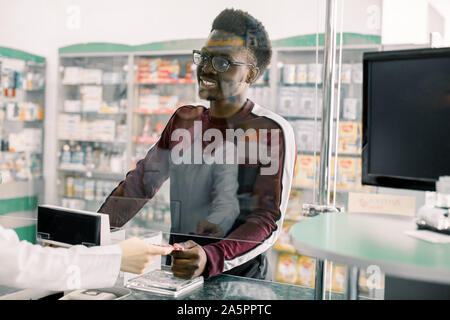 Donna farmacista dando pillole per uomo nero client in farmacia Foto Stock