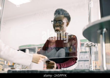 Donna farmacista dando pillole per uomo nero client in farmacia Foto Stock