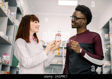 Donna speziale è consigliare la medicina per il giovane africano client in farmacia. Foto Stock