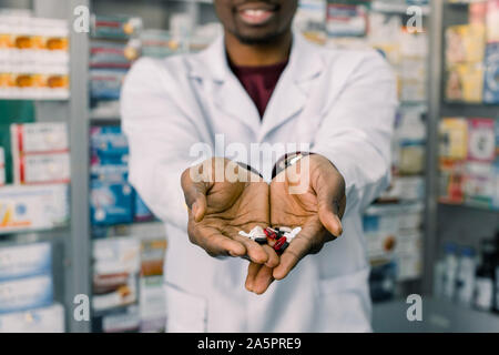 African-american farmacista uomo azienda compresse pillole nelle mani. Uomo con le mani in mano in possesso di una manciata di pillole medicinali per il trattamento di malattie Foto Stock