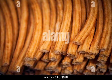 Pila di hot Madrid Churros impilati su un vassoio, disposti in fila. Close up churro bastoni pronto per essere servito Foto Stock