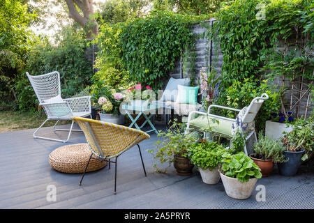 Mobili da giardino su decking con piante in vaso Foto Stock