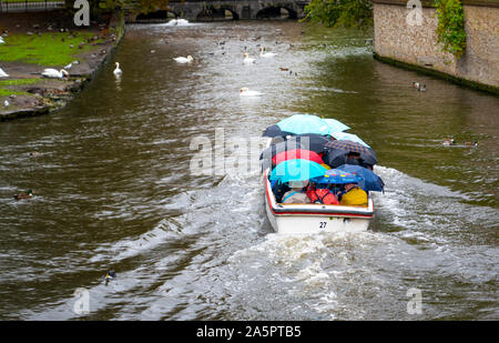 Bruges, Belgio - 11 Ottobre 2019: imbarcazione turistica va sotto la pioggia sul canal con cigni vicino Begijnhof. Foto Stock