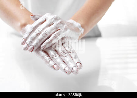 Bella e liscia la pelle a mano. La donna mette una maschera per la pelle della mano. Mano la cura della pelle. Foto Stock