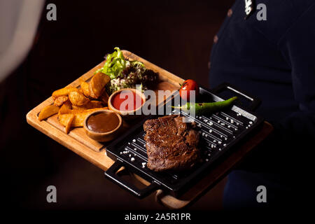Bistecca di manzo su mini padella per grigliare servito con patate fritte, insalata fresca Foto Stock