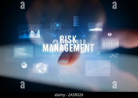 Dito toccando tablet con grafici e la gestione del rischio iscrizione, concetto aziendale Foto Stock