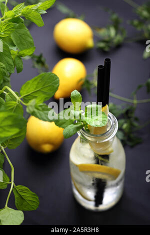 Bevande fredde. Acqua con limone, acqua in una bottiglia di vetro con limone e menta. Foto Stock