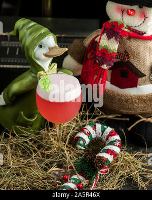 Red drink con schiuma bianca nel bicchiere guarnito con noce di cocco verde spruzza Foto Stock