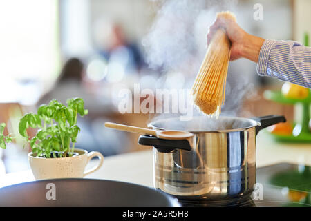 Mano di cuoco o cuocere gli spaghetti di contenimento sulla pentola con acqua bollente Foto Stock