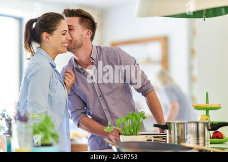 Contentissimo coppia giovane la cucina insieme in cucina a la stufa Foto Stock