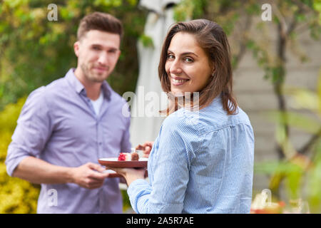 Giovane donna e il suo amico stanno avendo uno snack a una festa o a una festa estiva Foto Stock