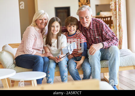Nipoti e nonni prendere un selfie con selfie stick nel soggiorno Foto Stock