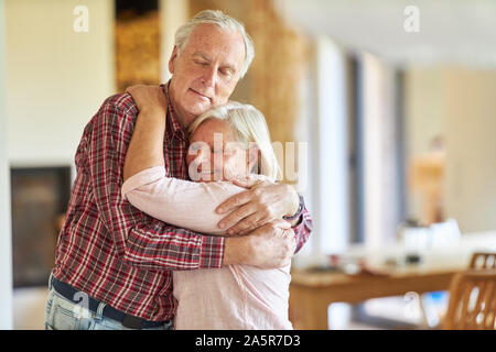 Senior amorosa giovane costeggiata ogni altra felicemente sorridente nel soggiorno Foto Stock