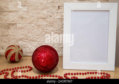 Natale mock up, biglietto di auguri, perle di rosso, rosso e oro palle di Natale e un muro di mattoni dello sfondo. Copia dello spazio. Le decorazioni di Natale. Foto Stock