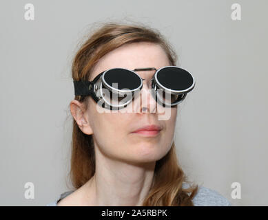 Giovane donna con nero occhiali saldatura sul suo capo Foto Stock