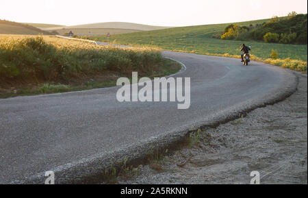 Giovane biker corse ad alta velocità e con la sua bici su asfalto nella parte anteriore Foto Stock