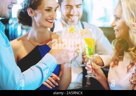 Gli uomini e le donne presso il bancone di un bar godendo le loro bevande Foto Stock