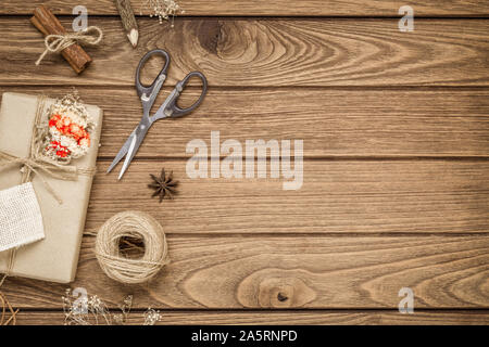 Realizzato a mano DIY regalo di Natale scatola su uno sfondo di legno. Presente naturale scatole per Natale e Capodanno o altro anniversario. Biglietto di auguri con copia sp Foto Stock