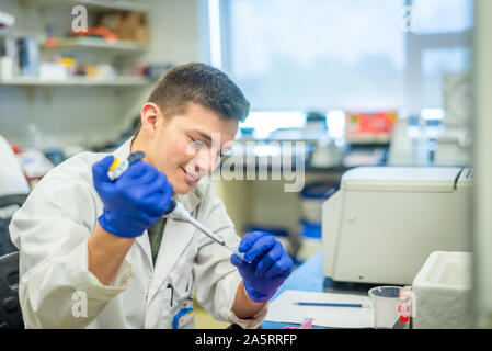 Giovane studente di scienze che effettua esperimenti biotecnologici in laboratorio Foto Stock