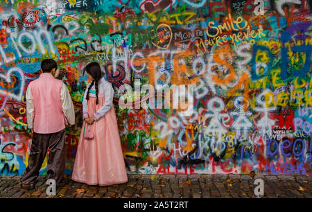 Una immagine di una coppia in costume tradizionale in posa di fronte al Muro di John Lennon (Praga). Foto Stock