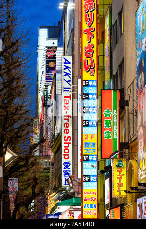 Tokyo, Akihabara, Chuo-dori street. Vista lungo gli edifici alti con illuminati al neon insegne pubblicitarie, negozi include Yoshinoya e Tax Free shop. Foto Stock