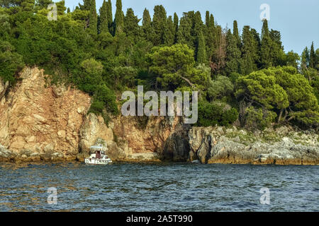 Tranquilla baia intima con una barca sulle sponde rocciose dell'isola rossa in Croazia, vicino alla città di Rovigno. Foto Stock