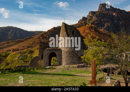 Rovinato mattone vecchia torre, parete e gate contro lo sfondo delle montagne e del cielo. Foto Stock