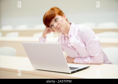 La donna lavora con un notebook nelle aule dell'università. Studia e prepara i compiti come studente e insegnante Foto Stock