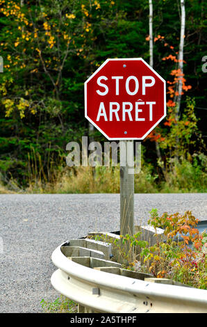 Un'immagine verticale di un bilingue segno di arresto situato nelle zone rurali del New Brunswick Canada. Foto Stock