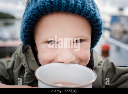 Close up ritratto di un ragazzo di bere cioccolata calda al di fuori del campeggio Foto Stock