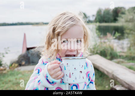 Giovane ragazza ridere bere cioccolata calda mentre camping all'aperto Foto Stock