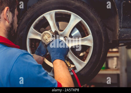 Sostituzione pneumatici invernali su pneumatici estivi in un garage professionale con l aiuto di strumenti professionali. Servizio moderno. Foto Stock