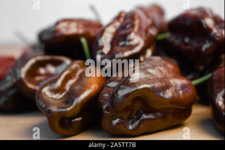 Gruppo di cioccolato habanero Peperoncino (Capsicum chinense) su un tavolo di legno. Marrone cioccolato Hot Chili Peppers. Gustosa la paprica, una delle più calde di pepe Foto Stock