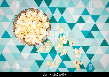 Pop corn in un recipiente isolato su bianco e lo sfondo blu Foto Stock