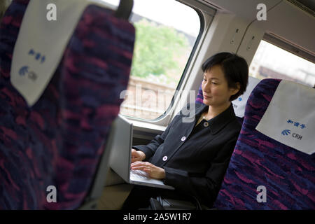 Metà donna adulta usando un computer portatile su un treno. Foto Stock
