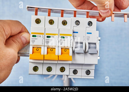 Interruttori miniaturizzati svolgono la doppia funzione di un interruttore e un fusibile. Elettricista è installato il collegamento della barra di distribuzione per i fusibili automatici. Foto Stock