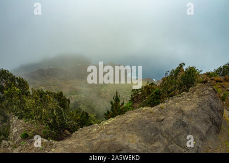 Stretta strada rurale nelle montagne del Parque Natural Majona. Basse nuvole umido appesa sopra il verdi pendii. Vista della parte nord-orientale di La Gomera Foto Stock