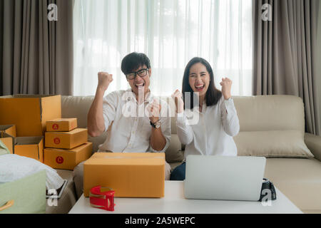 Asian l uomo e la donna stanno vendendo i loro online tramite il computer in casa e molto soddisfatti quando ci sono molti dei suoi ordini. Small business di avvio Foto Stock