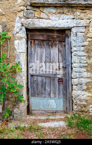 Il vecchio blocco porta di legno su una pietra fattoria abbandonata. Immagine Foto Stock